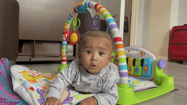 a baby is laying on the floor with a colorful toy in the background