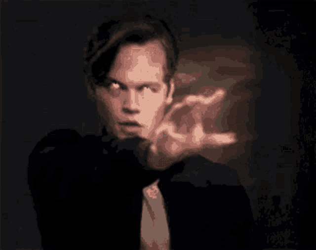 a man in a suit and tie is pointing with his finger