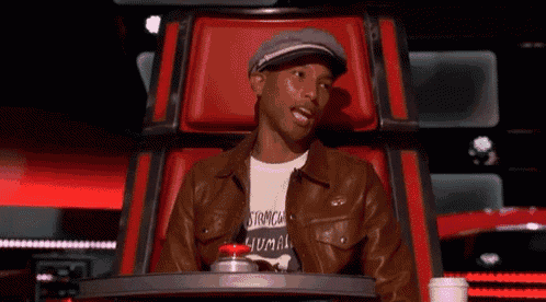 a man wearing a hat and a leather jacket is sitting in a chair on a television show .