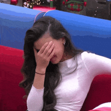 a woman covering her face with her hand while sitting on a couch .