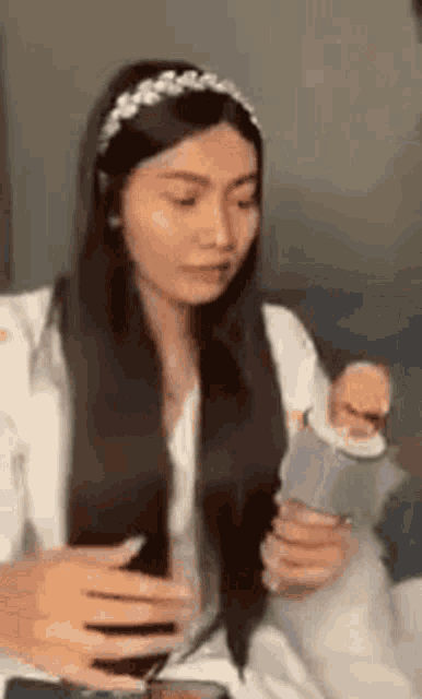 a woman with long black hair is holding a cell phone in her hand .