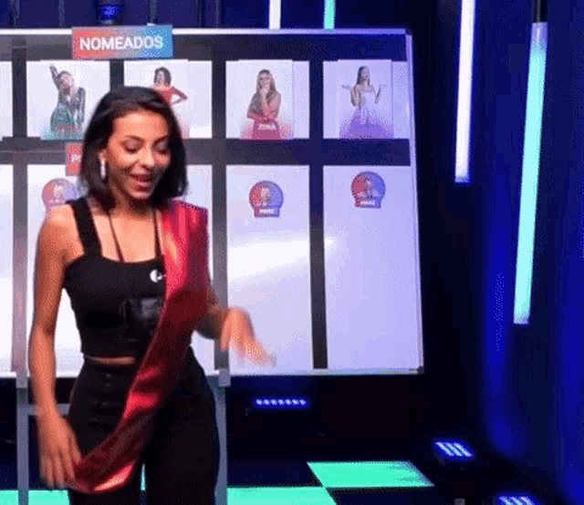 a woman is dancing in front of a sign that says ' nomeados ' on it