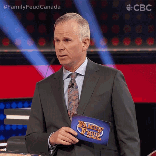 a man in a suit and tie holding a family feud card