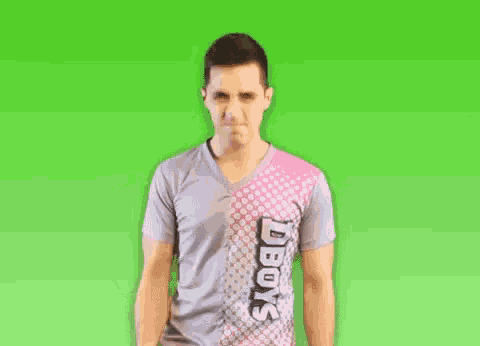 a man in a gray shirt is making a rock sign with his tongue out on a green screen .