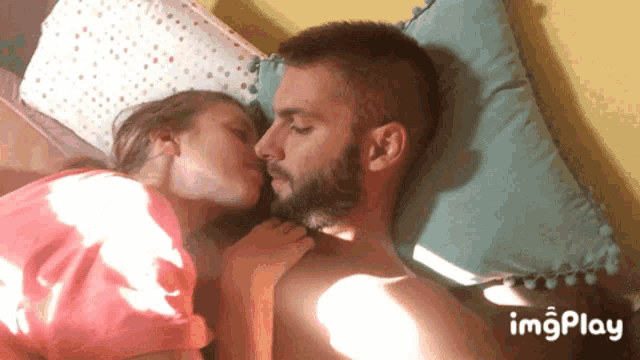 a man and a woman are kissing in bed with the words imgplay on the bottom right