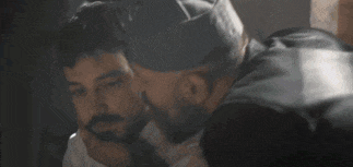 two men are talking to each other in a dark room