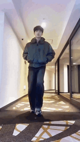 a man is walking down a hallway wearing a jacket .