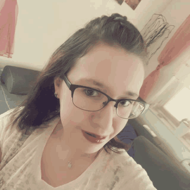 a woman wearing glasses is taking a selfie