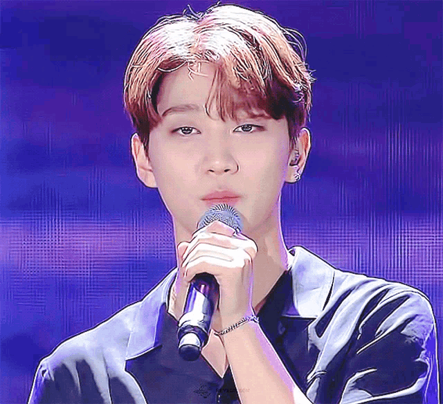 a young man singing into a microphone with a bracelet on his wrist that says " i love you "