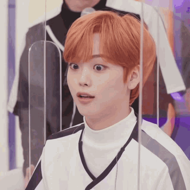 a young man with red hair is behind a glass barrier