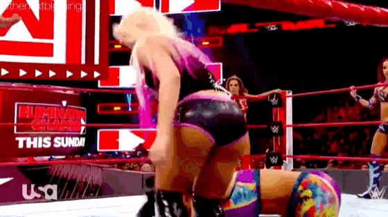 a woman is kneeling on another woman in a wrestling ring during a match .