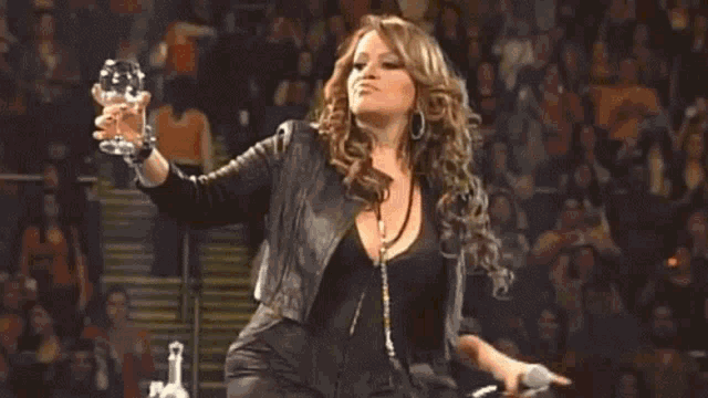 a woman is holding a glass of wine and a microphone while standing on a stage .