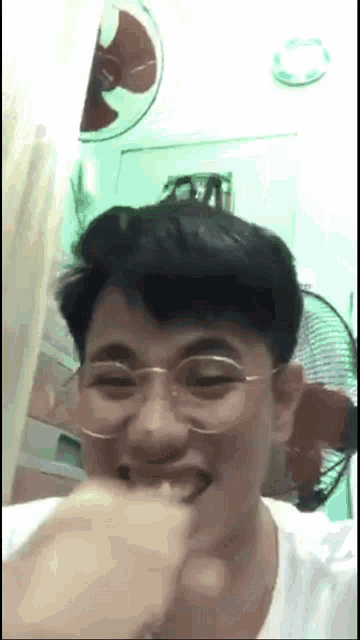 a man wearing glasses is biting another man 's finger .