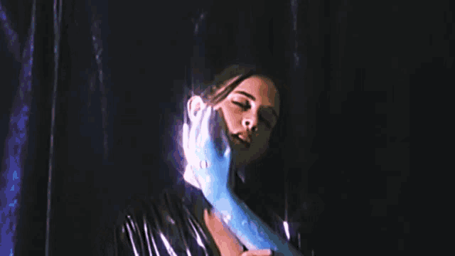 a woman with her eyes closed is being touched by a blue hand