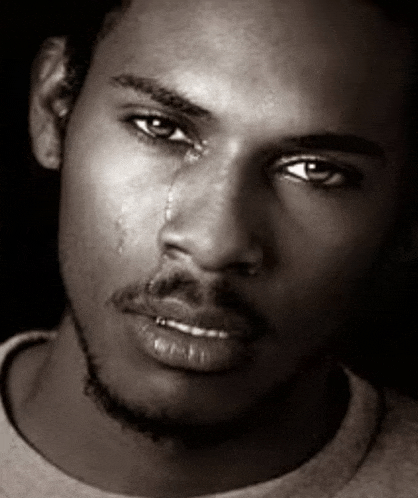 a black and white photo of a man crying with a tear coming out of his eye .