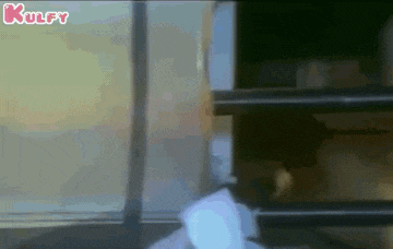 a man in a white hoodie is standing in front of a large window .