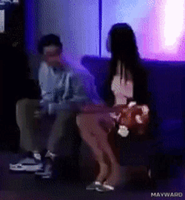 a man and a woman are sitting on a couch with mayward written on the bottom right corner