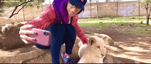 a woman taking a selfie with a lion cub in a zoo