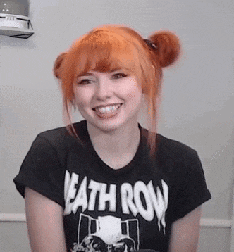 a woman with red hair is wearing a black t-shirt with the word death row on it and smiling .