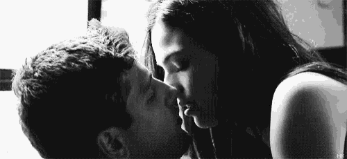 a man and a woman are kissing each other in a black and white photo .