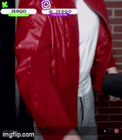 a man wearing a red jacket and a white shirt is standing in front of a brick wall .