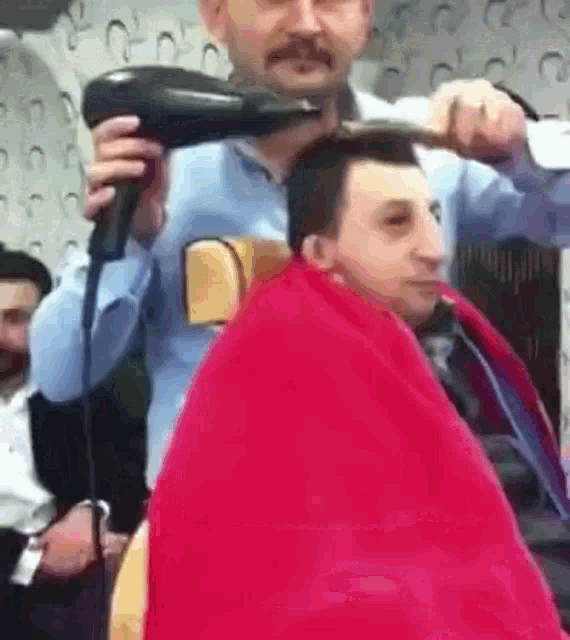 a man blow drying another man 's hair in a salon