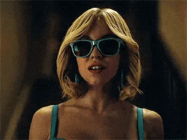 a woman wearing sunglasses and a blue top is looking at the camera .