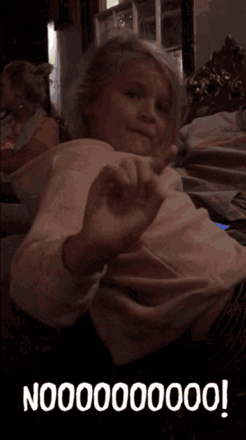 a little girl sitting on a couch with a cat behind her and the word no on the bottom right