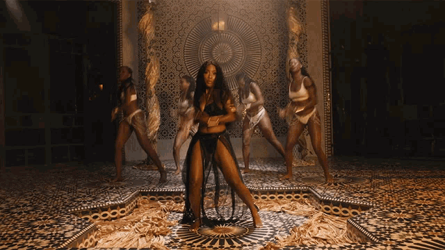 a group of women are dancing in front of a circular patterned wall