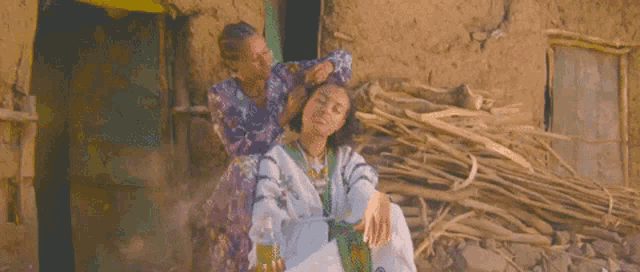 a woman is brushing another woman 's hair while sitting in front of a building .
