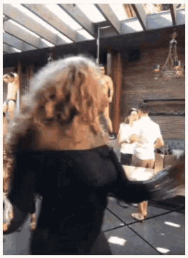 a woman in a black dress is dancing in a room