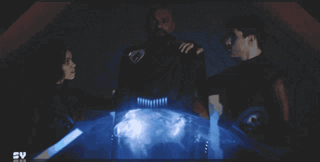 three people standing in front of a screen that says syfy on it