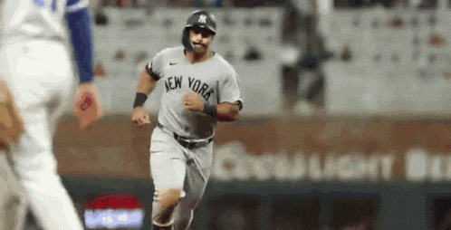 a new york yankees baseball player is running on the field during a baseball game .