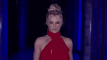 a woman in a red dress is standing in front of a blue wall .