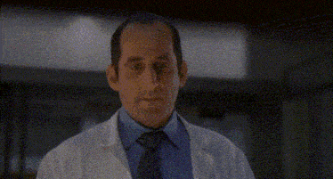 a man in a lab coat is holding a piece of paper with a picture of a man on it