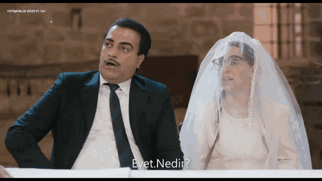 a man in a suit and tie sits next to a woman in a wedding dress who is asking " evet nedir "
