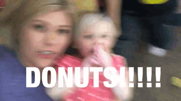 a woman is holding a little girl who is covering her mouth with her finger and says donuts