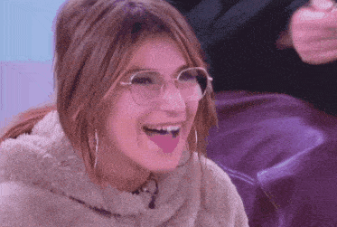 a woman wearing glasses is laughing with her tongue sticking out