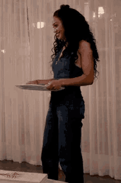 a woman in a denim jumpsuit is holding a tray in her hand .