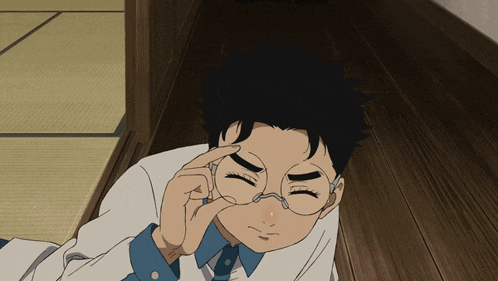 a young boy wearing glasses is laying on the floor
