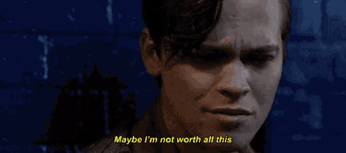 a man is standing in front of a blue brick wall and saying `` maybe i 'm not worth all this ''