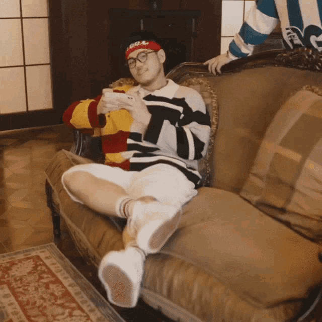 a man sitting on a couch wearing a headband that says ' supreme ' on it