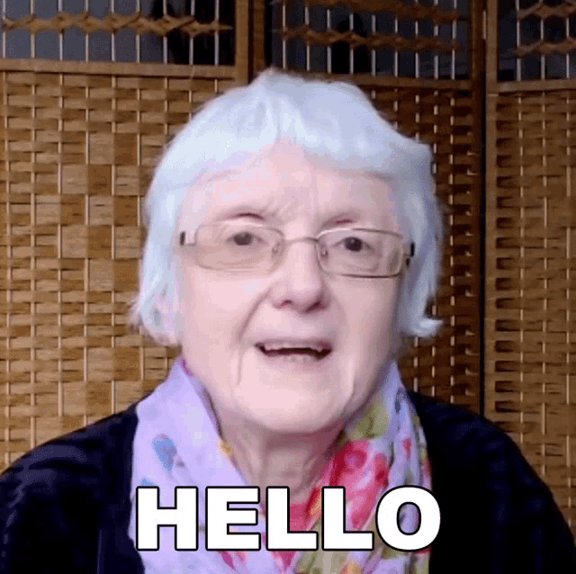 a woman with glasses and a scarf says hello