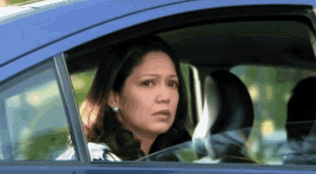 a woman is looking out the window of a blue car .