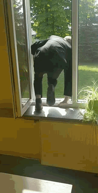 a man in a black suit is crawling out of a window .