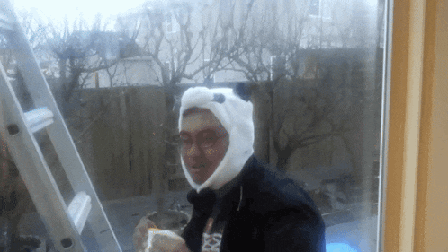 a man wearing a panda hat stands in front of a ladder