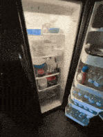 the inside of a refrigerator with the door open and bottles of water