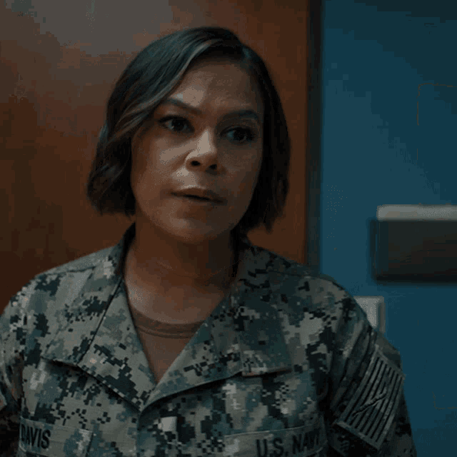 a woman in a camo uniform looks at the camera