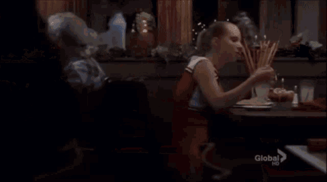 two cheerleaders are sitting at a table with a global hd sign in the background