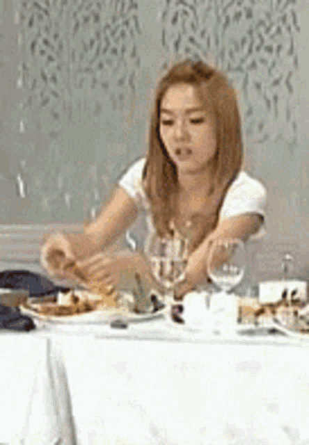 a woman is sitting at a table with plates and glasses of wine